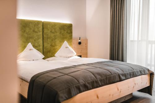a bedroom with a large bed with a green headboard at Lüch de Costa in Colfosco