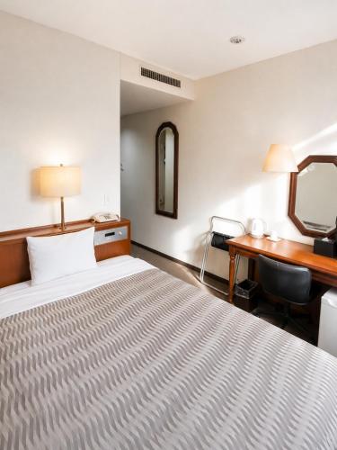 a hotel room with a bed and a desk at Kuretake-Inn Kakegawa in Kakegawa
