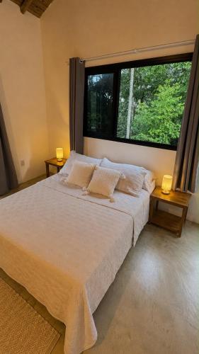 a bed in a bedroom with a large window at Suíte em Trindade, Praia Brava, na Mata in Paraty
