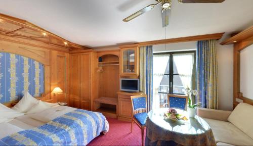a bedroom with a bed and a table and a tv at Hotel Augsburger Hof in Augsburg