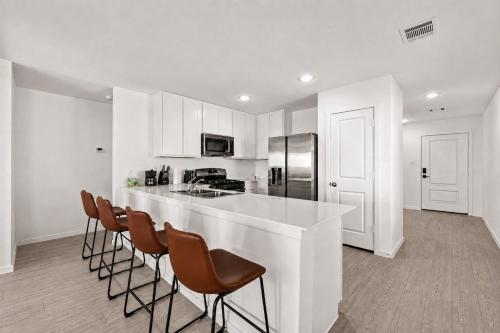 a white kitchen with a white counter and chairs at 3BR Near Gruene Historic District, Comal, and Guadalupe Rivers & Schlitterbahn in New Braunfels