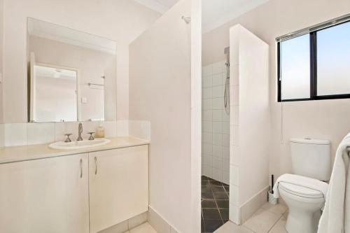 a white bathroom with a toilet and a sink at The Beachwood Nest in Broome