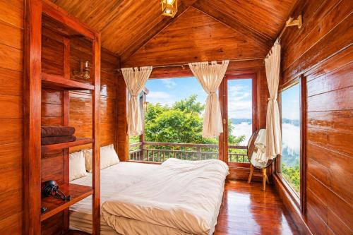 a bedroom with a bed and a large window at Mống Vàng Retreat Tà Xùa in Sơn La