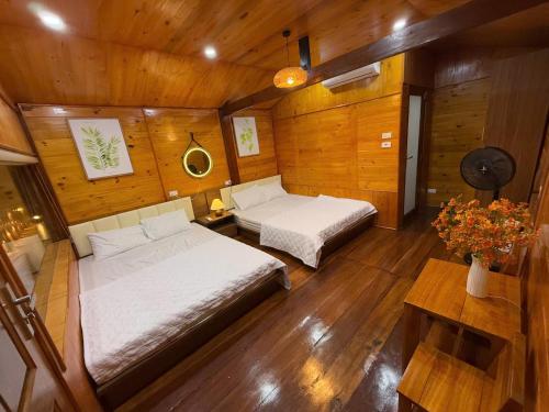 a bedroom with two beds in a wooden room at Honey Homes Cô Tô in Đảo Cô Tô
