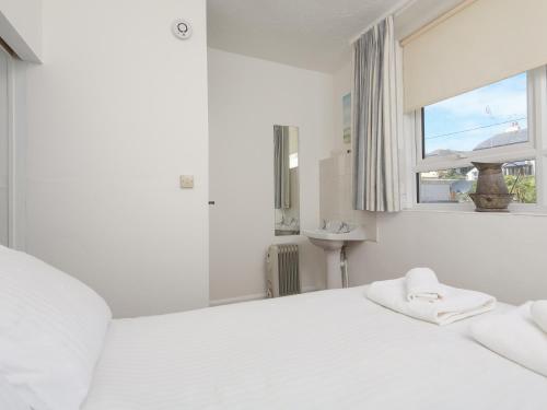 a white bedroom with a white bed and a window at 4 Thornlea Mews in Kingsbridge