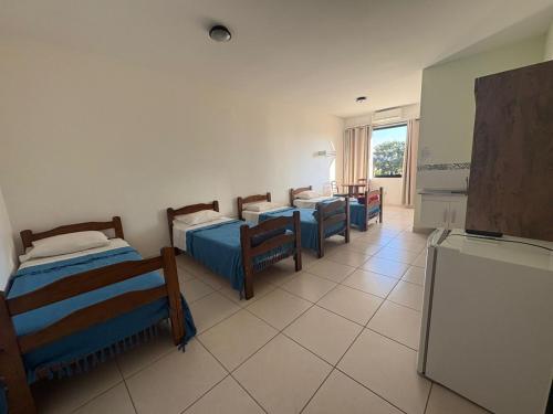 a room with three beds and chairs and a television at Hotel Flamboyant Taubate in Taubaté