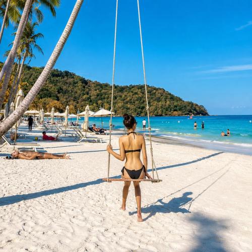 a woman in a bikini sitting on a swing on a beach at MAREVA KHEM BEACH HOTEL - Free Beach Shuttle in Phú Quốc