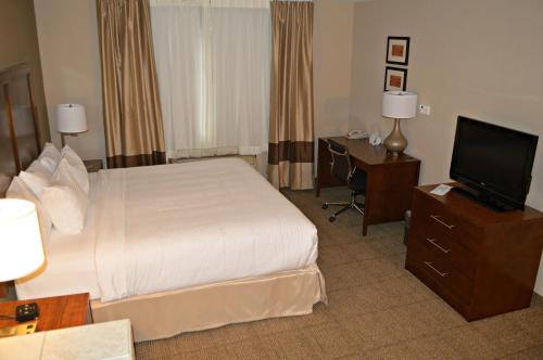 a hotel room with a bed and a flat screen tv at Wyndham Garden Hotel Cross Lanes Charleston in Charleston