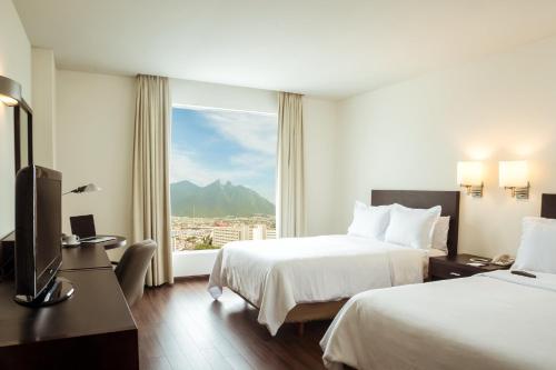 a hotel room with two beds and a window at Fiesta Inn Monterrey Tecnologico in Monterrey