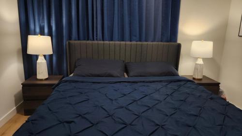 a bedroom with a bed with blue comforter and two lamps at TNC Stays Luxurious Modern Suite Seton Calgary South in Calgary
