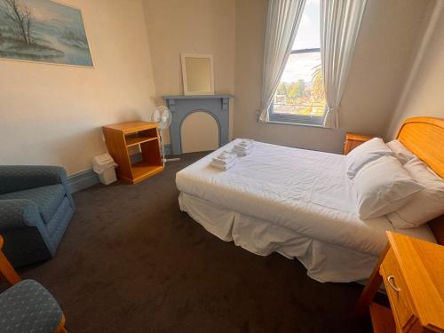 a bedroom with a bed and a chair and a window at The Leopold Hotel in Ararat