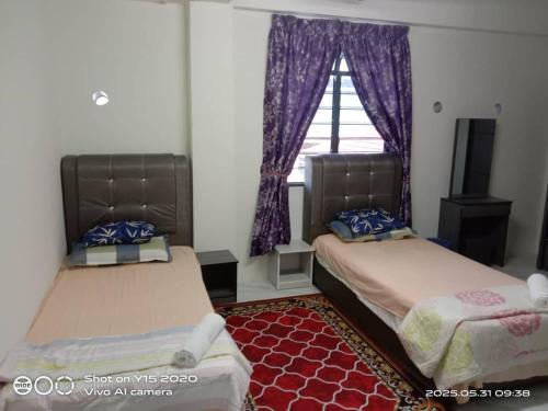 two beds in a room with a window at Qiffah Homestay in Kuala Terengganu