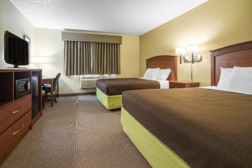 a hotel room with two beds and a flat screen tv at AmericInn by Wyndham Sioux Falls in Sioux Falls