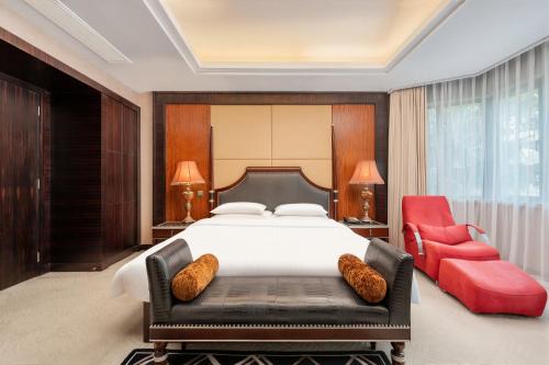 a bedroom with a large bed and a red chair at Greenland Mansion in Shanghai
