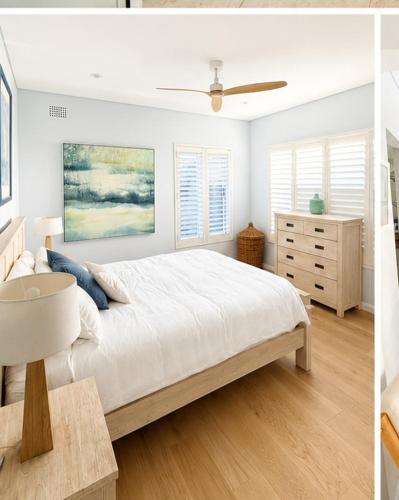 a white bedroom with a large bed and a dresser at Unique beach flat with own carpark area in Freshwater