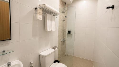a white bathroom with a toilet and a shower at Anamcara Hotel & Convention in Cipanas