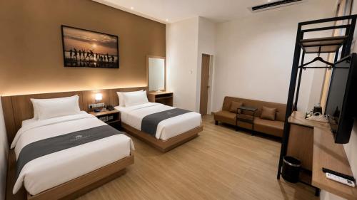 a hotel room with two beds and a couch at Anamcara Hotel & Convention in Cipanas