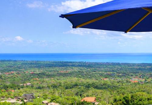 a blue umbrella flying over a city with the ocean at ELEVATE - Uluwatu, Bali in Uluwatu