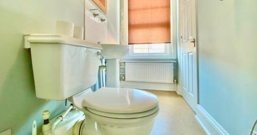 a white bathroom with a toilet and a window at The Loriston in Eastbourne