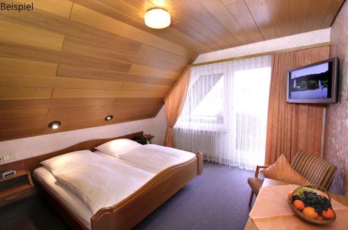 a bedroom with a bed and a table and a television at Gasthaus Seehof in Iznang