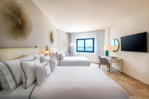 a hotel room with two beds and a flat screen tv at Meliá Casa Maya Cancún in Cancún