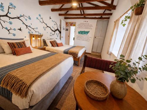a hotel room with two beds and a table at Valle verde, Hostel & camping in Urubamba