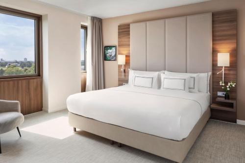 a bedroom with a large white bed and a window at Meliá Düsseldorf in Düsseldorf