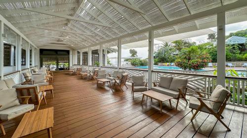 a porch with chairs and tables and a pool at Hotel Roatán Media Luna Resort, Affiliated by Meliá in First Bight