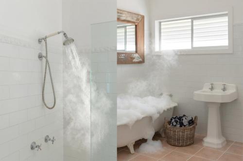 a bathroom with a shower and a sink and a tub at Bay Properties Pacific Lodge in Yamba