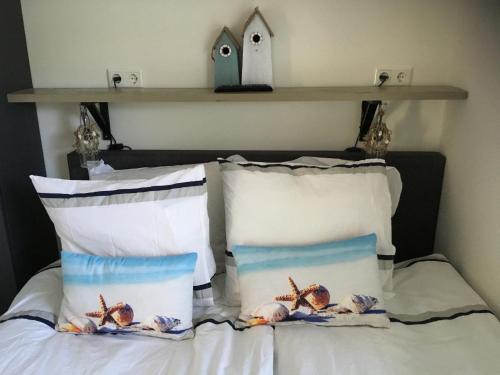 a bed with two pillows and a bird house on a shelf at Place2BEach-Bungalow in Noordwijk aan Zee