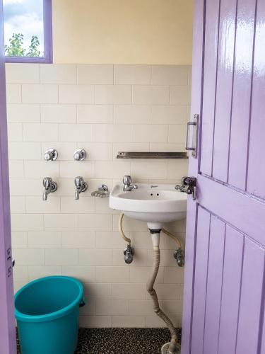 a bathroom with a sink and a blue bucket at Jain Residency in Manāli