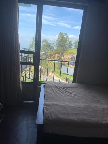 a bedroom with a bed and a view of a balcony at Thumb Up Family Rest in Haputale