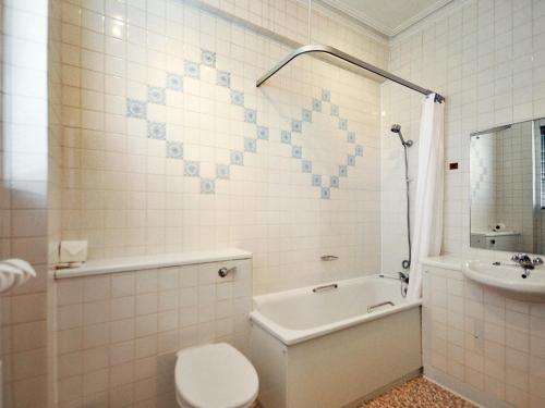 a bathroom with a toilet and a tub and a sink at Ardington Hotel in Worthing