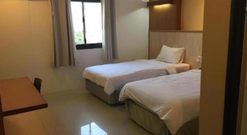 a hotel room with two beds and a window at Klim Hotel in Buriram