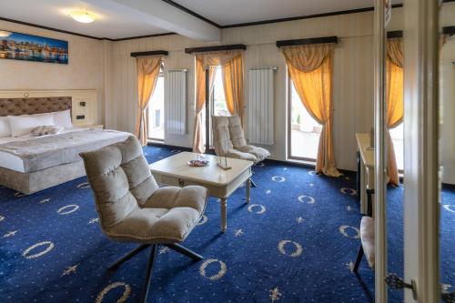 a bedroom with a bed and a chair and a table at Hotel Ambasador Iasi in Valea Lupului