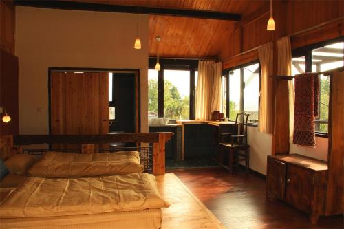 a bedroom with two beds and a kitchen with windows at Lijiang Baisha Free Time Designed Hotel in Lijiang
