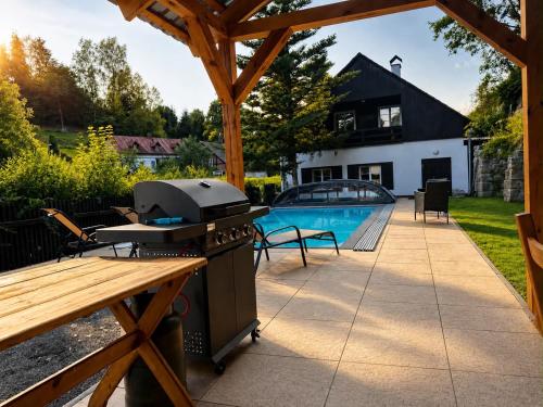 a patio with a grill and a pool at Chalupa Hnízdo Jetřichovice in Jetřichovice