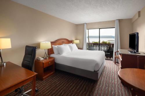 a hotel room with a bed and a desk and a television at Ramada by Wyndham Campbell River in Campbell River