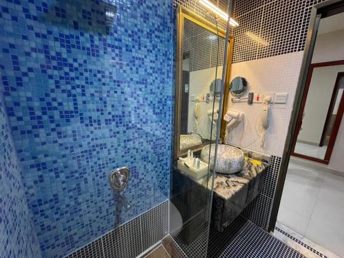 a blue tiled bathroom with a sink and a mirror at شير فل الرس in Ar Rass