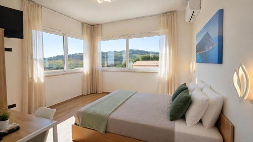 a bedroom with a bed and a desk and windows at Affittacamere Brezza Di Sirolo in Sirolo
