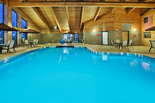 a large pool in a building with tables and chairs at AmericInn by Wyndham Aberdeen Event Center in Aberdeen