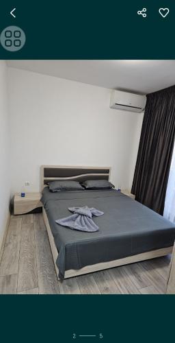 a bedroom with a bed with a gray comforter at Pensiunea LA ANI in Vadu