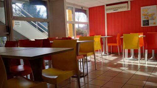 a dining room with tables and yellow chairs at Premiere Classe Grenoble Nord Moirans in Moirans