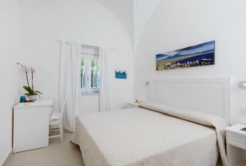 a white bedroom with a white bed and a window at Villa Pollio Guest House in Anacapri