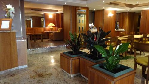 un hall d'hôtel avec deux plantes en pot et un restaurant dans l'établissement Residence Club Inn, à Nice