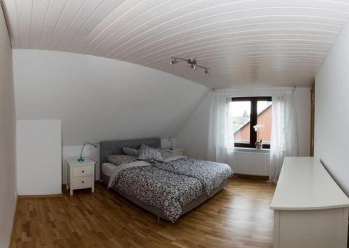 a white bedroom with a bed and a window at Appartement bei Kiel in Lilienthal