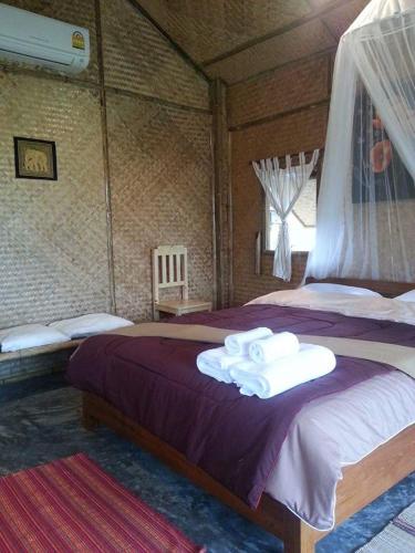 a bedroom with a large bed with towels on it at Tulip Resort Pai in Pai