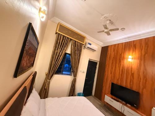 a bedroom with a bed and a tv and a window at Mario Suites Ltd in Kano