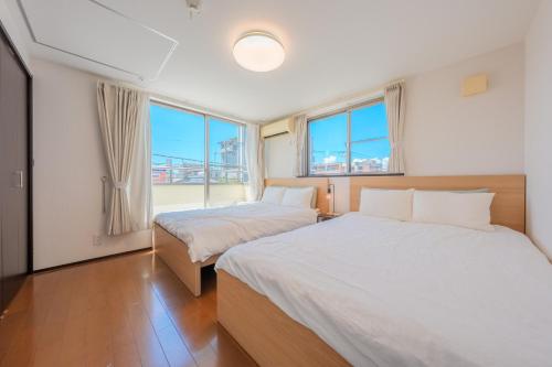 two beds in a room with two windows at FUJIMI TOWN HOUSE in Tokyo