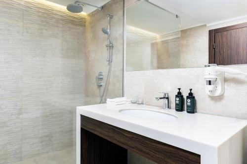 a bathroom with a white sink and a shower at Ramada Hotel & Suites by Wyndham Yerevan in Yerevan